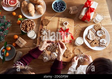 Draufsicht auf Mutter und Kind Tochter machen Weihnachtskekse Dekorationen über Tisch. Stockfoto