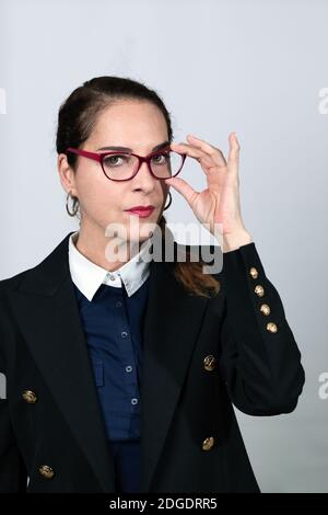 Nachdenkliche Frau suchen Kamera trägt Brillen, ein blaues Hemd und Jacke. Stockfoto