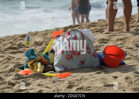 Objekte, Tragetasche und Spielzeug am Strand Sand, Urlaubskonzept, Sammlung von Dingen für den Urlaub am Meer, Stillleben Gegenstände, Gepäck Stockfoto