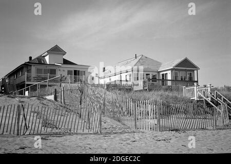 Zwei Sommerhütten erheben sich über einem verlassenen Strand außerhalb der Saison. Schatten weben zwischen einander durch Einzäunung auf dem Sand. Das Bild wurde auf einem aufgenommen Stockfoto