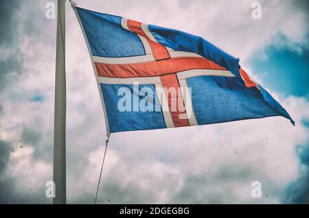 Winkende Flagge Islands gegen stürmischen Himmel Stockfoto