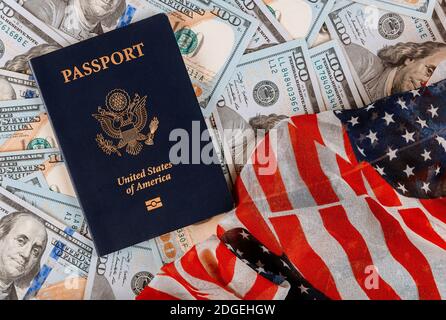 Patriotischer amerikanischer Pass auf einem Stapel von einem Hundert US-Banknotenwährungen auf amerikanischer Flagge Stockfoto