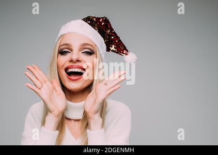 Lächelnd hübsche Dame trägt weißen Strickpullover und Santa Hut Und Spaß haben Stockfoto