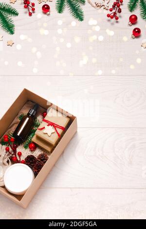 Geschenk-Box mit Bio-Öko-Kosmetik auf Holzhintergrund mit Dekorationen und Leuchten. Zero Waste Weihnachten oder Neujahr Konzept. Flach liegend, Draufsicht Stockfoto