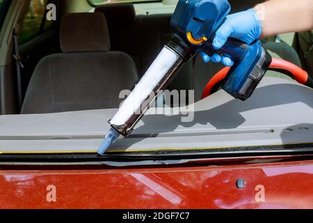 Nahaufnahme Auto Glasur Arbeiter Silikon-Kleber eine Windschutzscheibe eines Autos an einer Tankstelle. Stockfoto