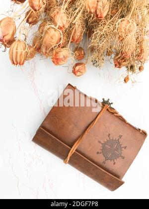 Getrocknete Blumen und ein Lederheft Stockfoto