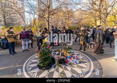 New York, Usa. Dezember 2020. Menschen versammelten sich um Strawberry Field Stellen Sie sich Mosaik im Central Park in New Yoko am 8. dezember 2020 John Lennon 40 Jahre nach seinem Tod zu erinnern. John Lennon wurde 40 Jahre an diesem Tag des 8. Dezember getötet. Der Dakota, in dem er und Yoko Ono in dieser Zeit lebten, sichtbar im Hintergrund. (Foto von Lev Radin/Sipa USA) Quelle: SIPA USA/Alamy Live News Stockfoto