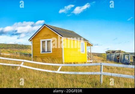 Verlassene gelbe kleines Haus mit weißem Zaun in der Landschaft Stockfoto