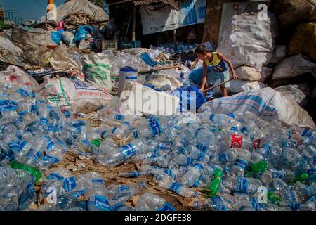 Osman Gony (10) sortiert zusammen mit seinem Vater Muhammad Kohir in ihrer Recycling-Werkstatt in Kolatoli nahe dem Strand in Cox's Bazar in Bangladesch Plastikflaschen. Osman hilft seiner Familie, während die Schule wegen COVID nicht da ist. Der sortierte Kunststoff zahlt 20 Cent pro Kilo. Gelegen an einem der längsten Strände der Welt, ist die Gegend seit Jahren ein Touristenziel. Mit den Abwässern und dem Müll als offensichtlichem Nachdenken steht die Infrastruktur in der Stadt unter neuem Druck mit einer schnell wachsenden Bevölkerung. Die Region beherbergt auch die weltweit größten Flüchtlingslager für die Rohingyas, die fl Stockfoto