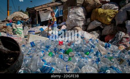 Osman Gony (10) sortiert zusammen mit seinem Vater Muhammad Kohir in ihrer Recycling-Werkstatt in Kolatoli nahe dem Strand in Cox's Bazar in Bangladesch Plastikflaschen. Osman hilft seiner Familie, während die Schule wegen COVID nicht da ist. Der sortierte Kunststoff zahlt 20 Cent pro Kilo. Gelegen an einem der längsten Strände der Welt, ist die Gegend seit Jahren ein Touristenziel. Mit den Abwässern und dem Müll als offensichtlichem Nachdenken steht die Infrastruktur in der Stadt unter neuem Druck mit einer schnell wachsenden Bevölkerung. Die Region beherbergt auch die weltweit größten Flüchtlingslager für die Rohingyas, die fl Stockfoto