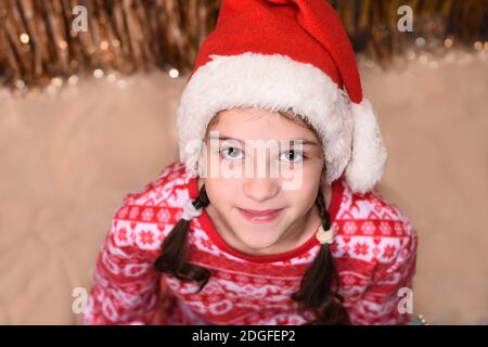 Mädchen santa's Helfer suchen nach oben. Neujahrsfest. Lustige Baby Santa. Schönes Mädchen trägt roten weihnachtsmann Hut feiert weihnachtstag. Stockfoto