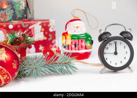 weihnachtsmann Schlitten, Geschenkboxen, Fichtenzweig, Wecker und Schneemann auf Holz weißen Hintergrund Stockfoto