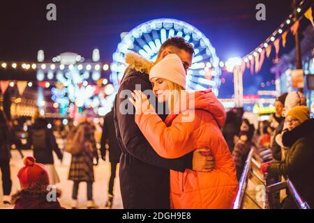 Schönes Paar Eislaufen Im Stadtzentrum. Junges Paar Schlittschuhlaufen auf einer öffentlichen Eisbahn im Freien. Thematische Eislaufbahn Stockfoto