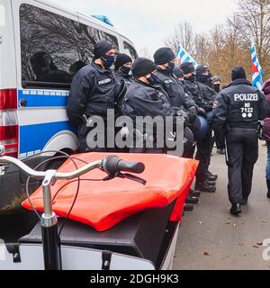 Braunschweig, 05. Dezember 2020: Gruppe schwarz-uniformierter deutscher Polizisten stehen mit dem Rücken zu einem blau-weißen Polizeiwagen Stockfoto