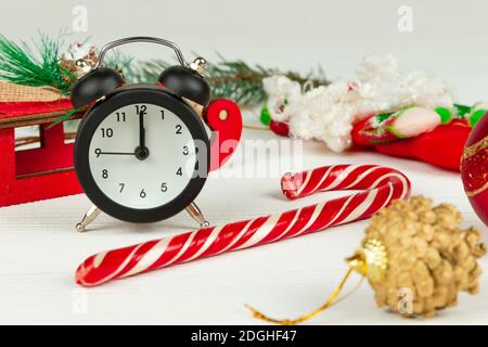 santa claus Schlitten, Wecker, santa claus Stab, goldenen weihnachtsbaum Kegel und Boxen mit Geschenken auf weißem Holz Hintergrund mit goldenen Adern Stockfoto