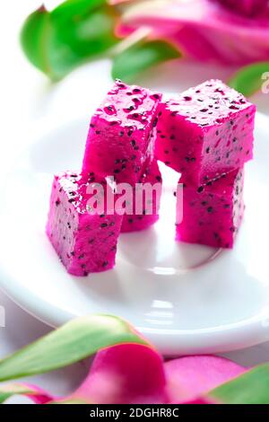 Rosa Drachenfrucht, Pitaya oder Pitahaya in Würfel geschnitten auf weißem Teller auf dem Tisch. Trendiges Superfood. Stockfoto