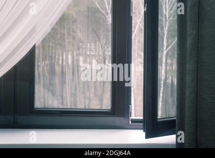 Fragment eines teilweise geöffneten Fensters mit Vorhängen Stockfoto