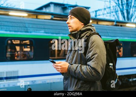 Sopot Fast Urban Bahnhof. Junger Mann steht und wartet Zug auf Plattform. Tourist reist mit dem Zug. Porträt Von Caucas Stockfoto