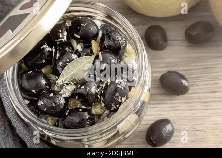 Eingepickte Oliven in einem Glasbecher mit Deckel. Stockfoto