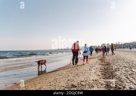 Im Winter laufen die Menschen am Sandstrand. Perfekter Winterurlaub. Die Leute entspannen sich in der kalten Jahreszeit an der Küste. Danzig, Polen Februar Stockfoto