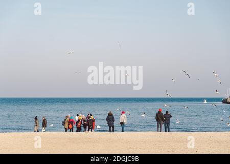 Polen, Sopot, 9. Februar 2020. Menschen am Strand in Sopot. Menge am Strand im Winter. Genießen Sie den Tag im sonnigen Winter in der Nähe des Meeres. Stockfoto
