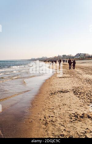 Im Winter laufen die Menschen am Sandstrand. Perfekter Winterurlaub. Die Leute entspannen sich in der kalten Jahreszeit an der Küste. Danzig, Polen Februar Stockfoto