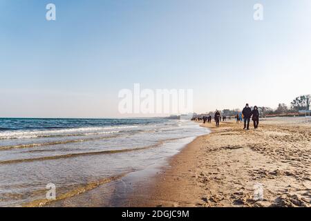 Im Winter laufen die Menschen am Sandstrand. Perfekter Winterurlaub. Die Leute entspannen sich in der kalten Jahreszeit an der Küste. Danzig, Polen Februar Stockfoto