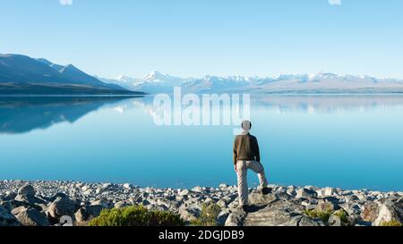 Tourist steht am Ufer des Sees Pukaki und beobachtet Mt Cook reflektiert in den klaren Gewässern Stockfoto