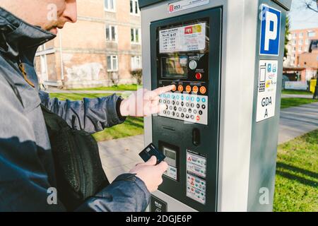 Man zahlt für das Parken mit einer Kreditkarte mit NFS-Technologie. Einfache Zahlung. Zahlungsprozess im Automatenparkplatz. Zahler Stockfoto