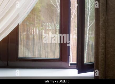 Fragment eines teilweise geöffneten Fensters mit Vorhängen Stockfoto