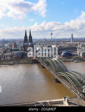 Vertikales Stadtbild über dem Rhein der Kölner Stadt (Kölner Dom, Hohenzollernbrücke und Colonius) Wolkenverhangener blauer und weißer Himmel im Hintergrund. Stockfoto