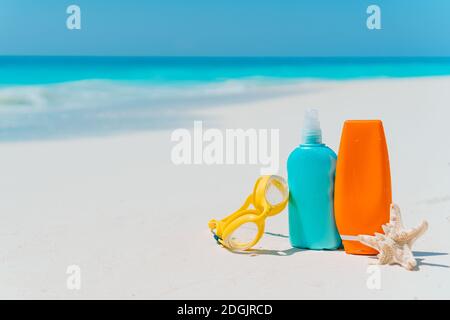 Sonnencreme-Flaschen, Sonnenbrillen, Seesterne am weißen Sandstrand Stockfoto