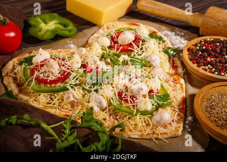 Pizza vor dem Backen, Gemüse und Gewürze auf dunklem Holzhintergrund Stockfoto