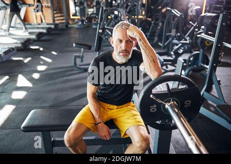 Sportler mit leerstehender Optik auf der Bank sitzend Stockfoto