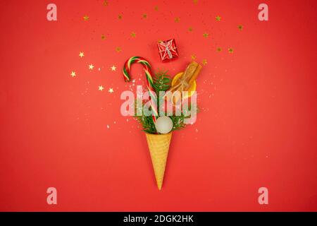 Ein Waffelkegel ist voll von Konfetti, bunten Zuckerrohr, getrocknete Orange, Zimt und ein kleines Geschenk für den Urlaub Stockfoto