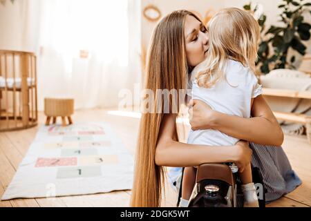 Junge Mutter umarmt und küsst ihre kleine Tochter Stockfoto