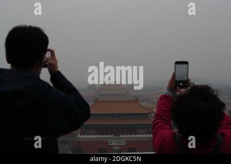 --FILE--Blick nach unten aus Wanchun Pavillon im Jingshan Park, die Verbotene Stadt ist in Smog gehüllt, und die gelbe Warnung für schwere Luftverschmutzung ist s Stockfoto