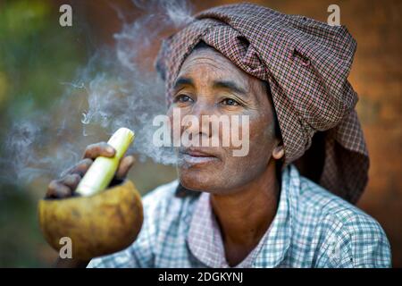 Eine alte Frau raucht am 10. Januar 2013 im Dorf Indein in der Nähe des Inle Lake Myanmar eine Cheerot, eine lokale Zigarre Stockfoto