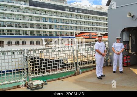 Matrosen auf dem Deck des neuseeländischen Navy-Schiffes HMNZS Canterbury. Im Hintergrund ist ein Kreuzfahrtschiff Stockfoto