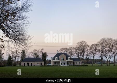 HOGE HEXEL, NIEDERLANDE - Nov 23, 2020: Moody Bunte dramatische Dämmerung Herbst Sonnenuntergang Himmel über einem zeitgenössischen Bauernhaus mit Grünland vor Stockfoto