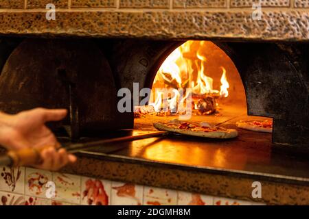 Eine Pizza wird in einen Holzofen gestellt Ein Restaurant in Rom Stockfoto