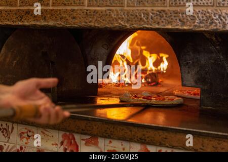 Eine Pizza wird in einen Holzofen gestellt Ein Restaurant in Rom Stockfoto