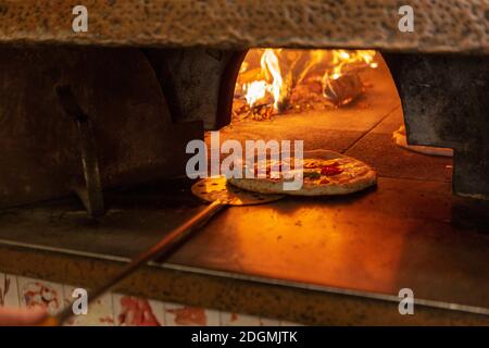 Eine Pizza wird in einen Holzofen gestellt Ein Restaurant in Rom Stockfoto