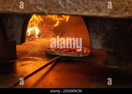 Eine Pizza wird in einen Holzofen gestellt Ein Restaurant in Rom Stockfoto