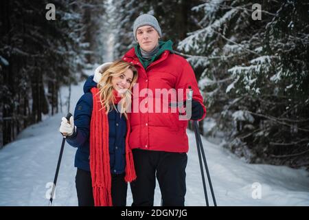 Ein Spaziergang im Fichtenwald auf Skiern bringt Freude und Glück für ein junges Ehepaar. Stockfoto