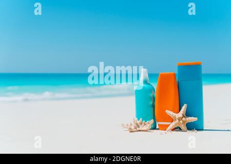 Sonnencreme-Flaschen, Sonnenbrillen, Seesterne am weißen Sandstrand Stockfoto