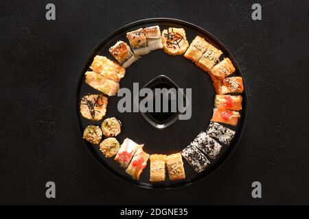 Sushi-Set als Weihnachtskranz serviert mit Sojasauce auf schwarzem Hintergrund. Blick von oben. Stockfoto