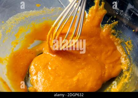 Eigelb mit einem Silikon-Schneebesen in einer transparenten Schüssel Stockfoto