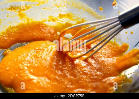 Eigelb mit einem Silikon-Schneebesen in einer transparenten Schüssel Stockfoto