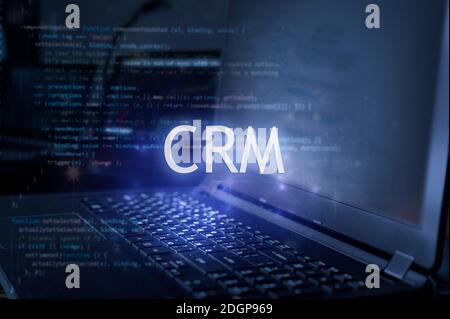 CRM-Inschrift gegen Laptop und Code-Hintergrund. Customer Relationship Management-System. Stockfoto